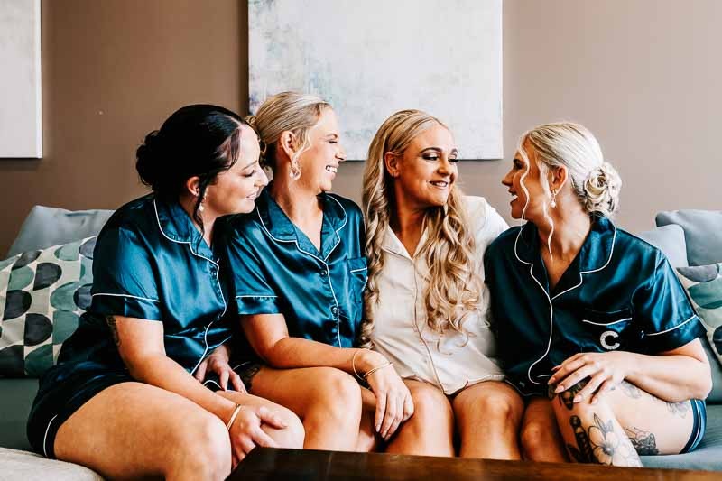 Bride and bridesmaids sit on couch