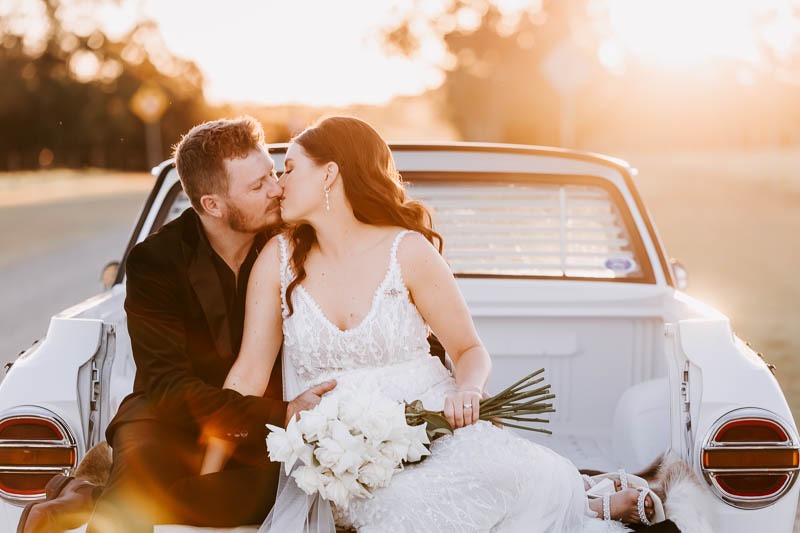 Bride & Groom kiss in the back of a vintage ute
