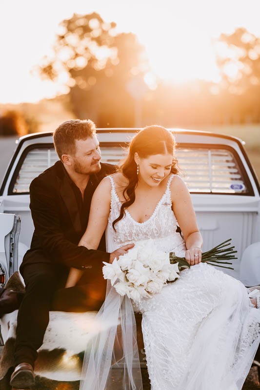 Bride & Groom laugh in the back of a vintage ute