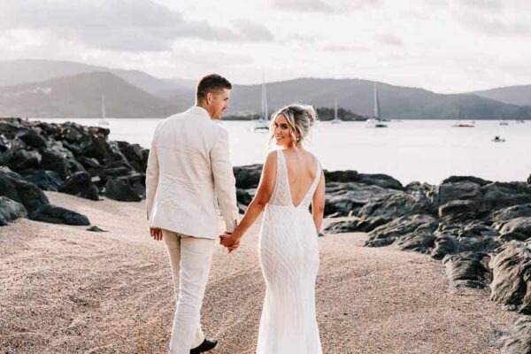 Bride & Groom hold hands and walk on beach