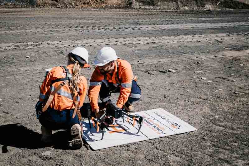 Drone operators setting up drone for flight on mine site