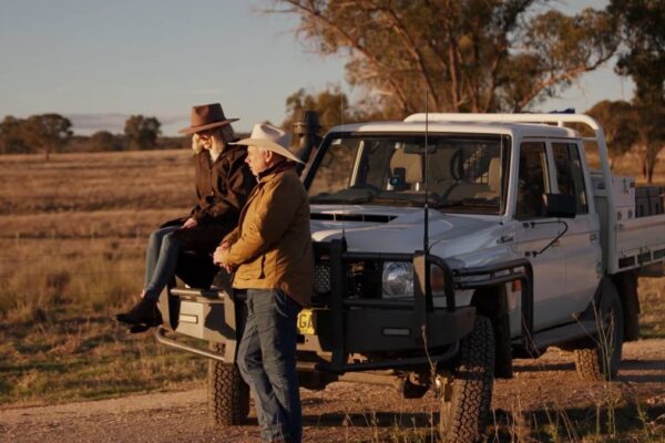 two people waerings drizabone sitting on landcruiser