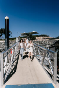 FCTA May22-Th3rd Dimension Media-LR-14 Flight Centre staff walking along Coral Sea Marina dock under sunny skies