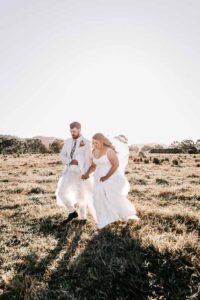 Professional videography captures couple walking in sunlit field