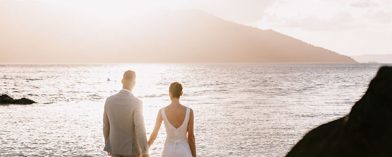Professional videography, photography, and drone footage of newlyweds on a beach during sunset