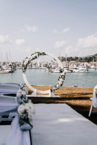 Professional videography at waterfront wedding with floral arch