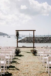 Professional videography, photography, and drone footage of a beach wedding setup with rows of white chairs.