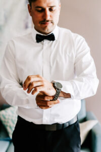Professional videography man adjusting watch in formal attire