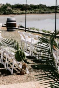 Professional videography, photography, and drone footage of a serene outdoor wedding setup by the water.