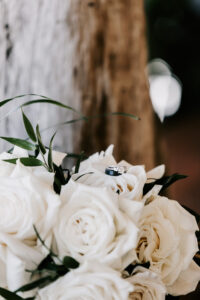 Professional videography capture of wedding rings on white roses