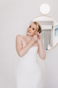Professional videography bride adjusting earrings in white dress