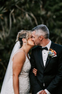 Professional videography, photography, and drone footage: Elegant wedding couple kissing in garden setting