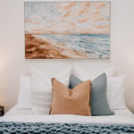 Bedroom with coastal artwork and blue bedding