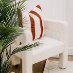 Armchair with a rust-striped cushion beside indoor plants