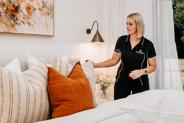 The Stylist arranging cushions on a bed