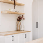 Kitchen shelving with vases above white cabinetry