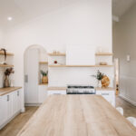 Timber kitchen island facing a cooker and open shelves