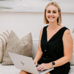 The Stylist seated on a sofa with a laptop