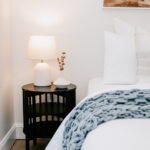 Bedside lamp beside a bed with a blue patterned throw