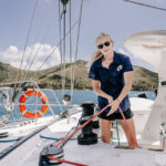 Professional videography capturing sailor adjusting sail ropes