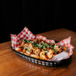 Professional videography, photography, and drone footage of savory loaded fries in basket on wooden table