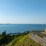 Professional videography, photography, and drone footage of a coastal landscape with a winding road and sea views