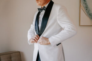 Professional videography elegant man in a white tuxedo adjusting suit