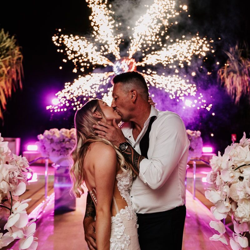 bride and groom kissing in front of fireworks