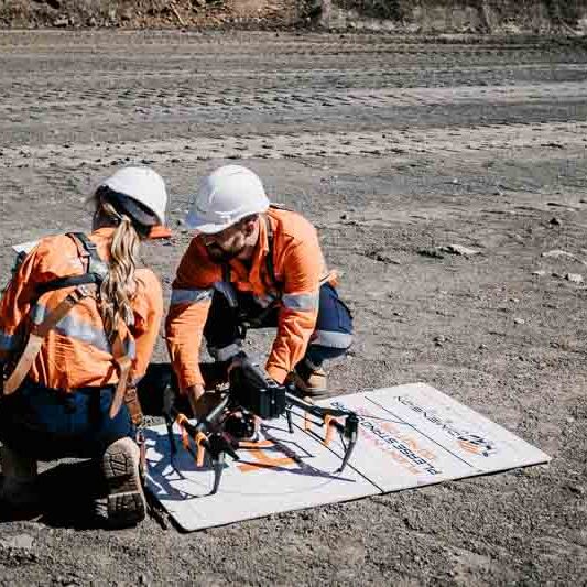 Drone operators setting up drone for flight on mine site