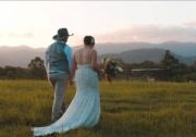 bride and groom walk through field